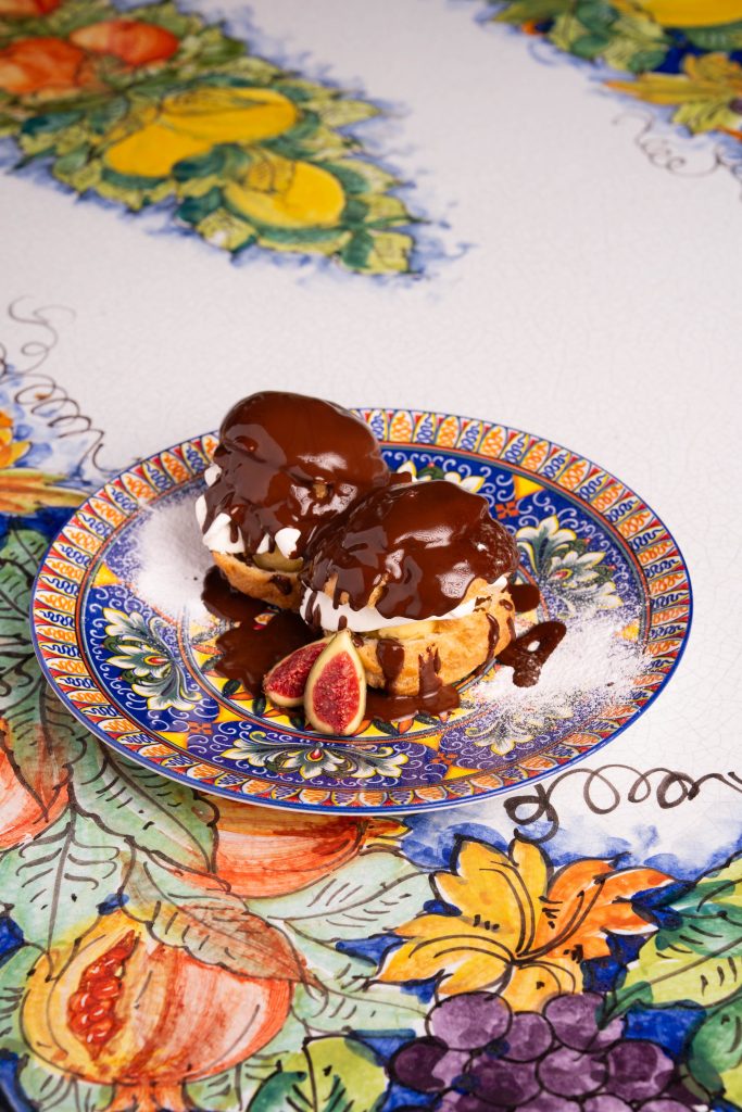 Profiteroles nappées de chocolat chaud servies sur une assiette en céramique sicilienne à Mougins